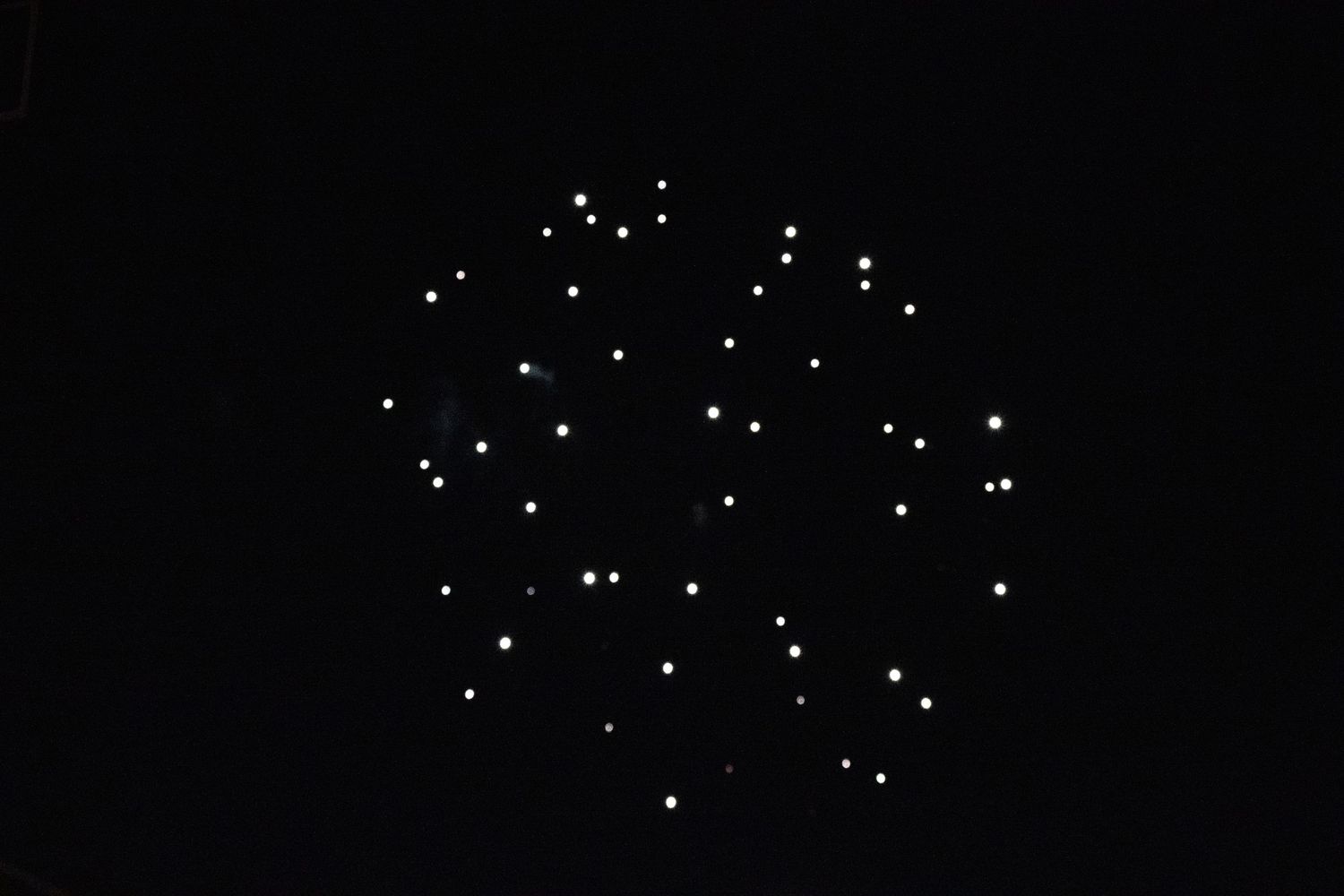 White dotted firework pattern forming spherical shape in night sky.
