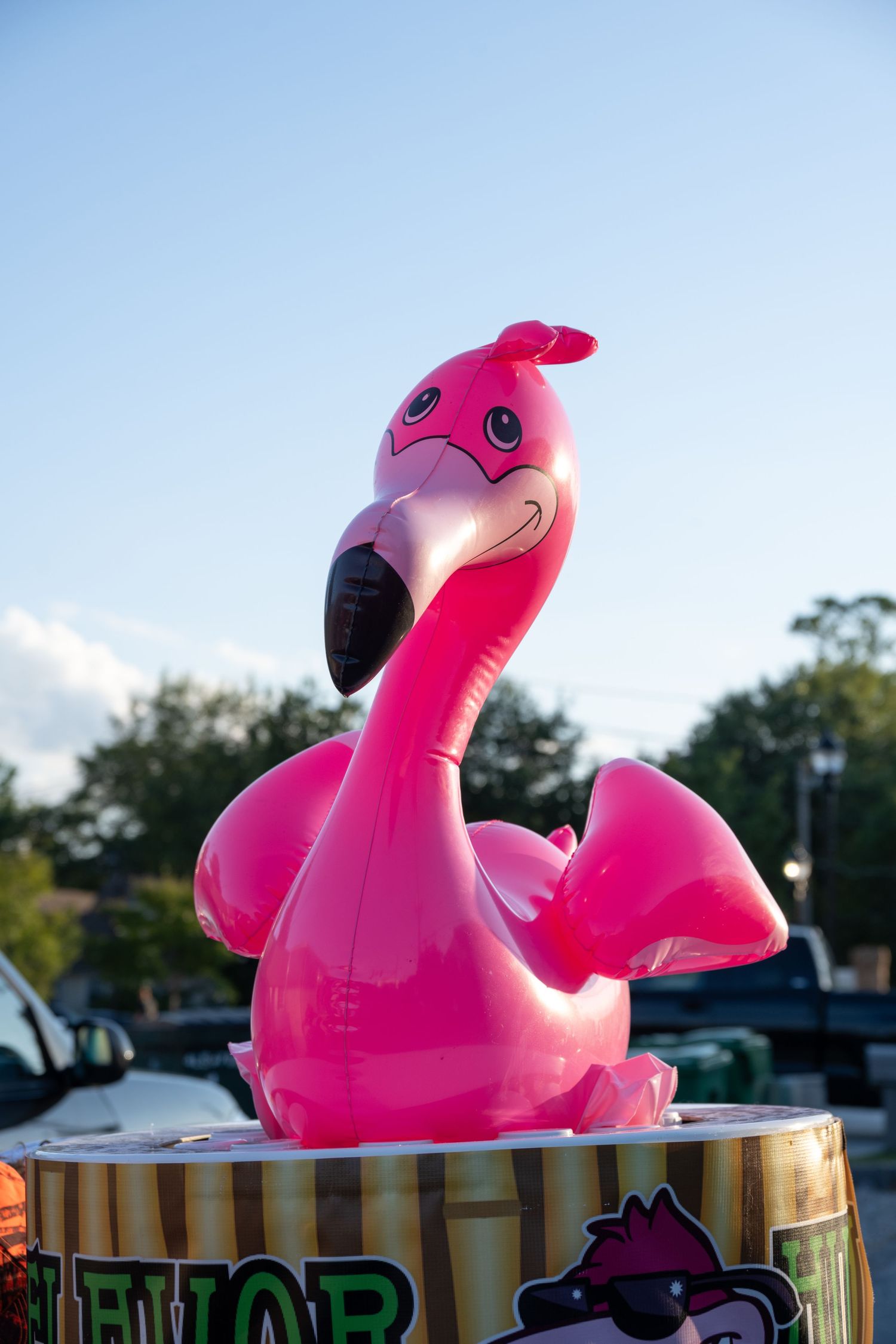 Pink inflatable flamingo decoration on display stand outdoors.