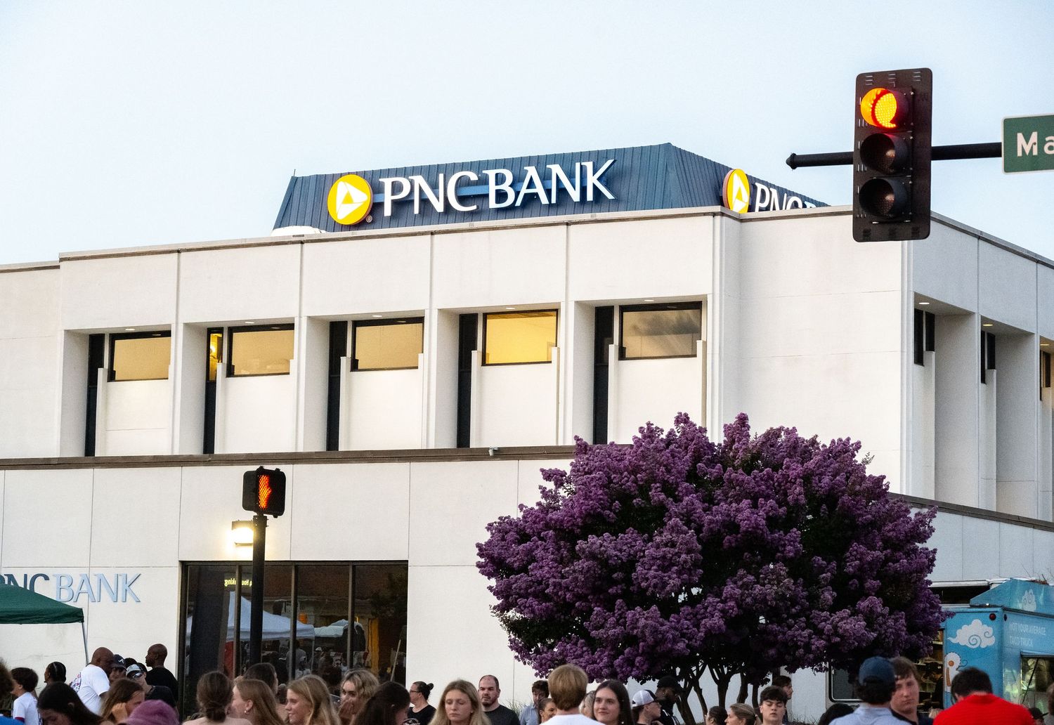 PNC Bank branch exterior with purple flowering tree on a city street corner.