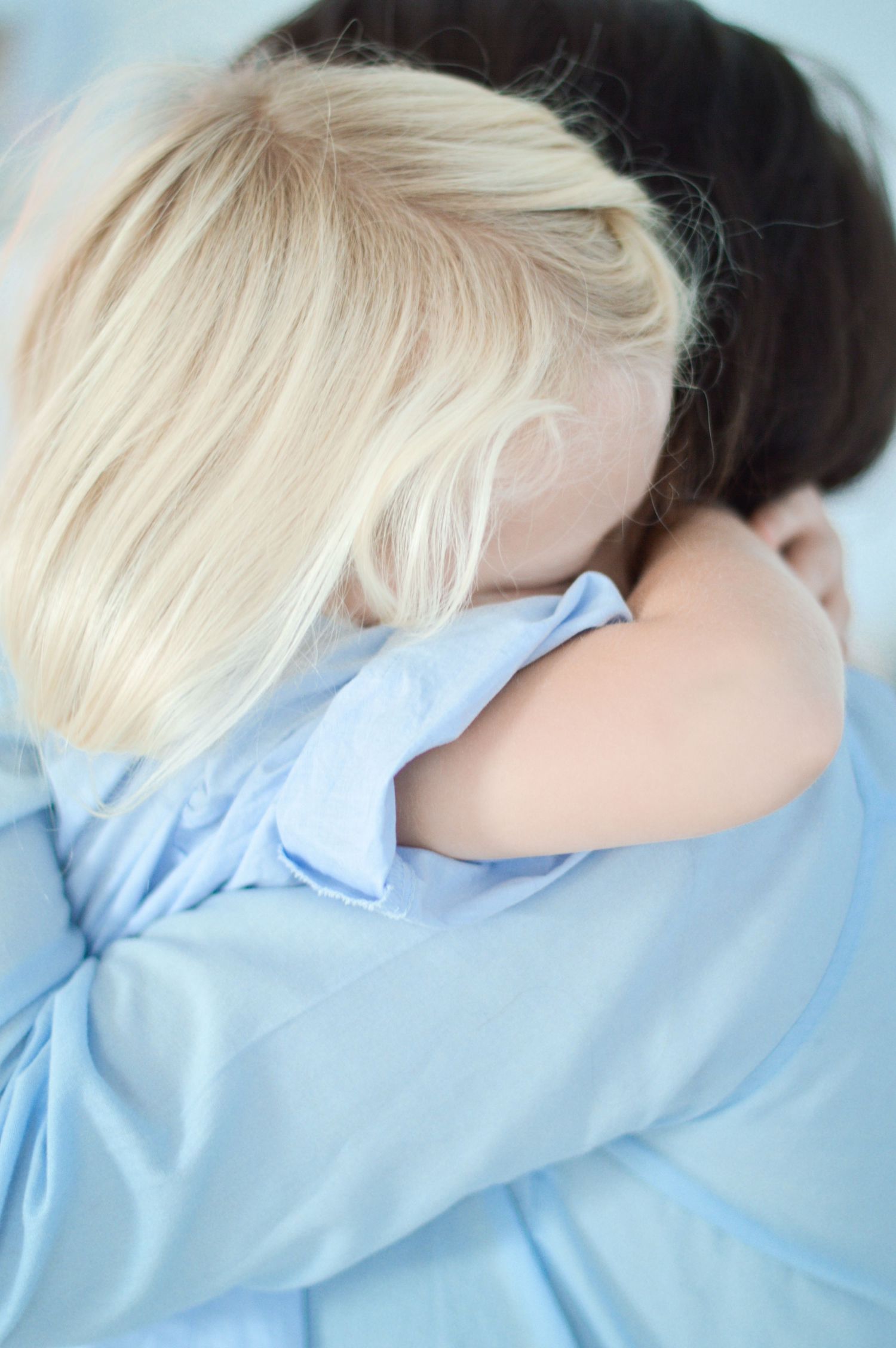 Ein junges, blondes Mädchen und ihre Mama umarmen sich innigst.