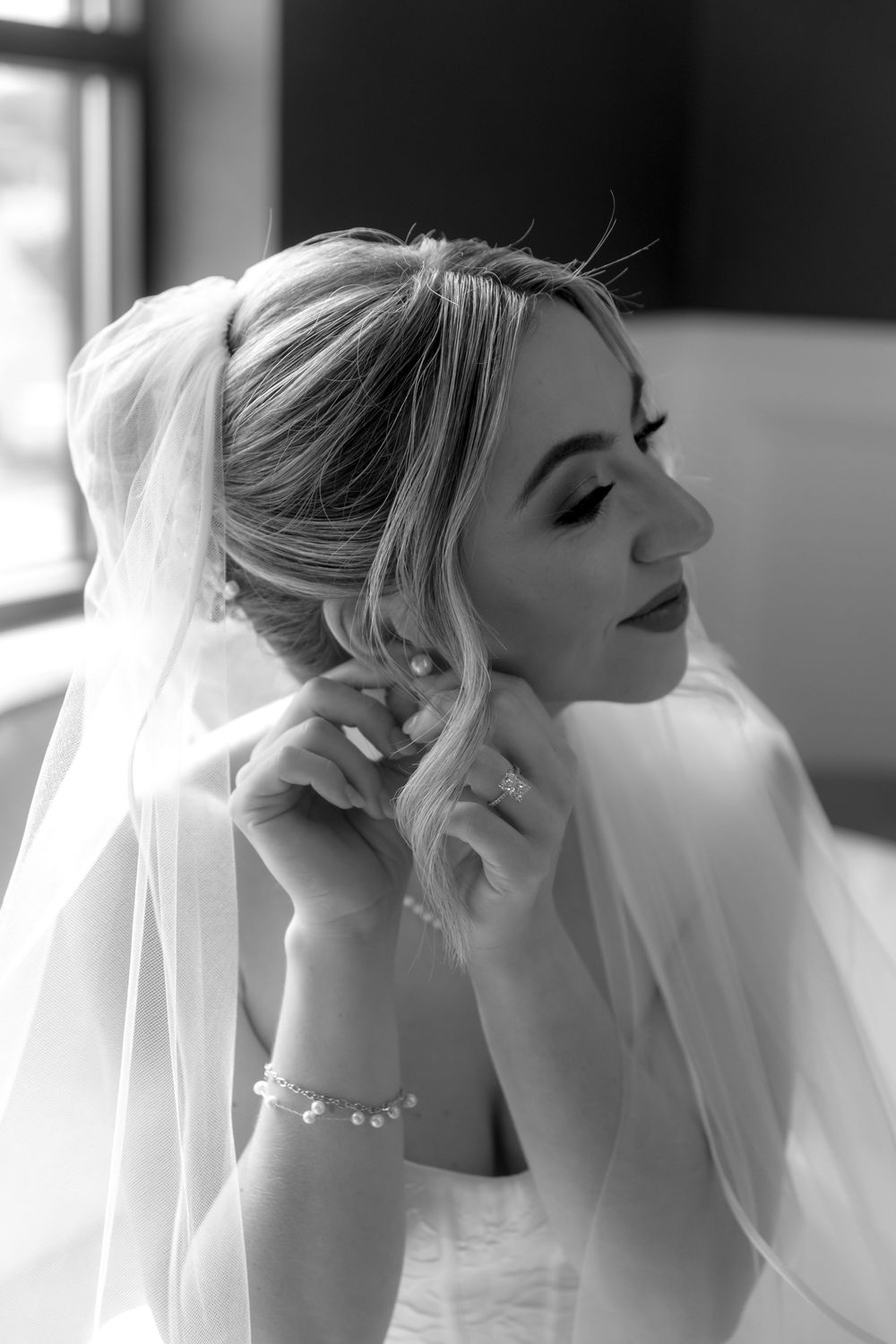 Delicate details of a wedding veil and jewelry in black and white photography.
