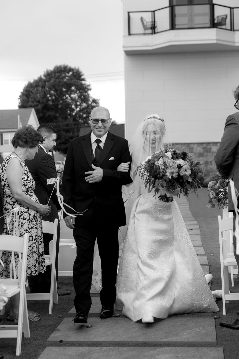 Black and white photos capturing intimate wedding ceremony moments with guests seated in white chairs.