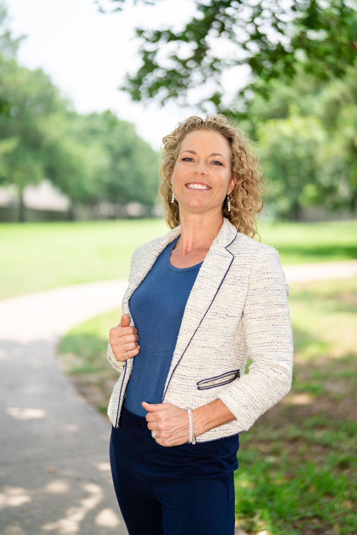 Professional portrait in a park setting with natural greenery background.