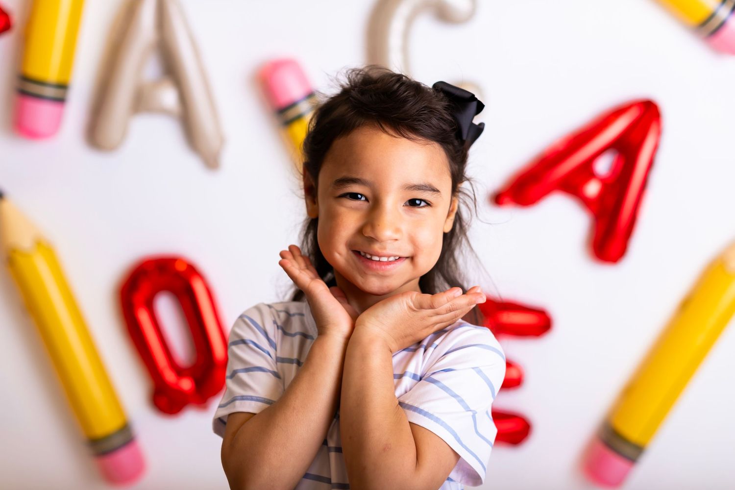 Cheerful young student posing against wall decorated with letters and pencils.