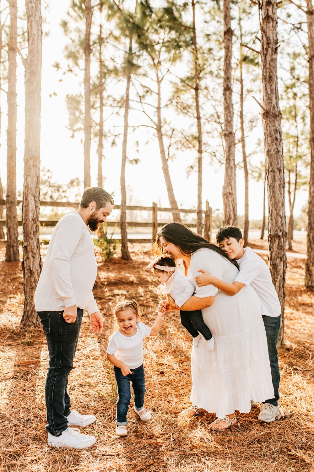Family photo session in pine forest during golden hour sunlight.