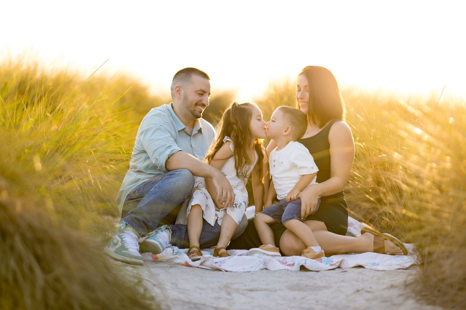 Family relaxing together on a blanket during sunset in a natural outdoor setting.