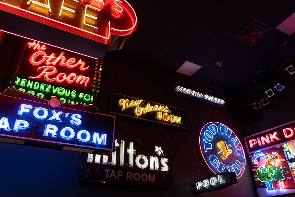 Collection of vintage neon signs glowing in vibrant colors at night.