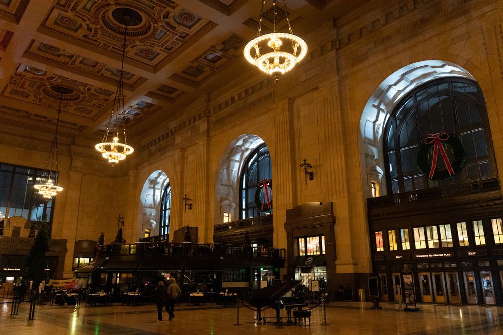Historic train station interior with ornate ceiling, grand chandeliers and arched windows creating an elegant atmosphere.