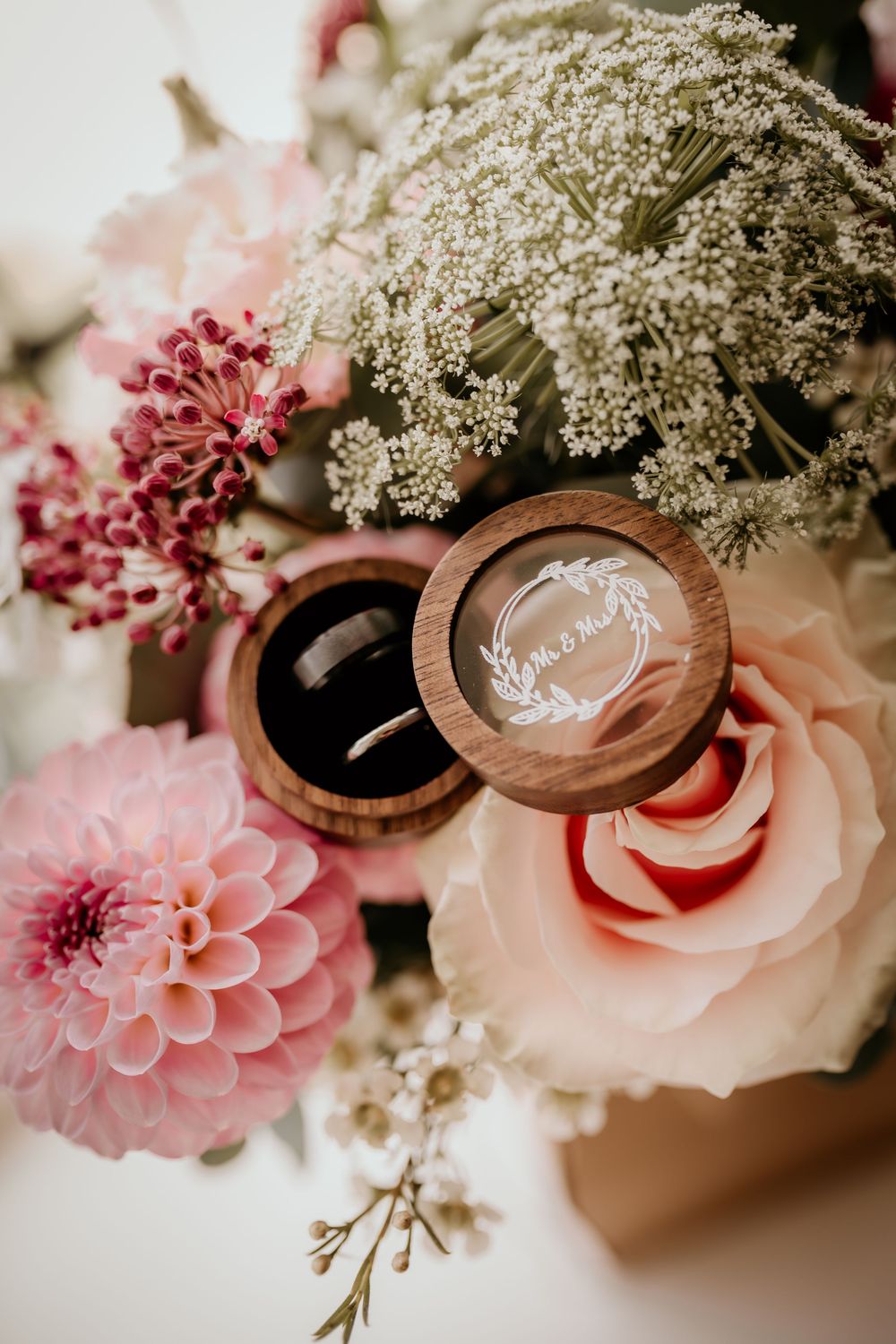 Wooden wedding ring boxes with delicate pink dahlias and white Queen Anne's lace flowers arranged artistically.