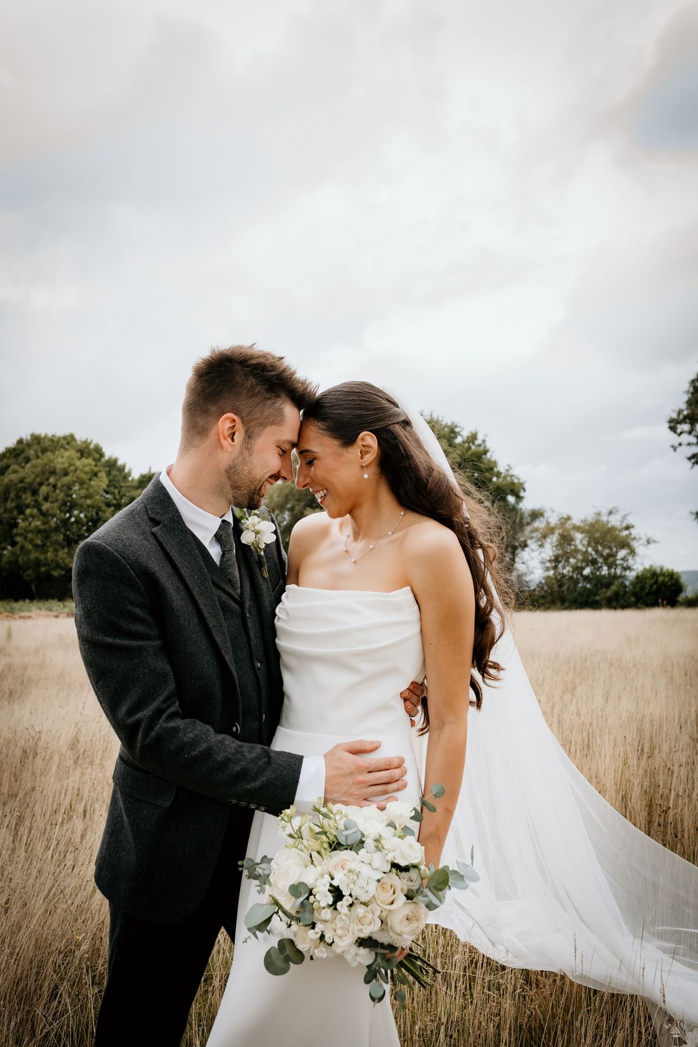 A romantic wedding couple shares intimate moments in a golden wheat field on their special day.