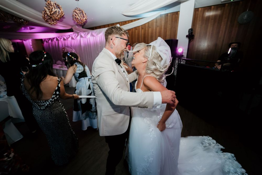 Bride and groom sharing first dance at wedding reception with purple ambient lighting.