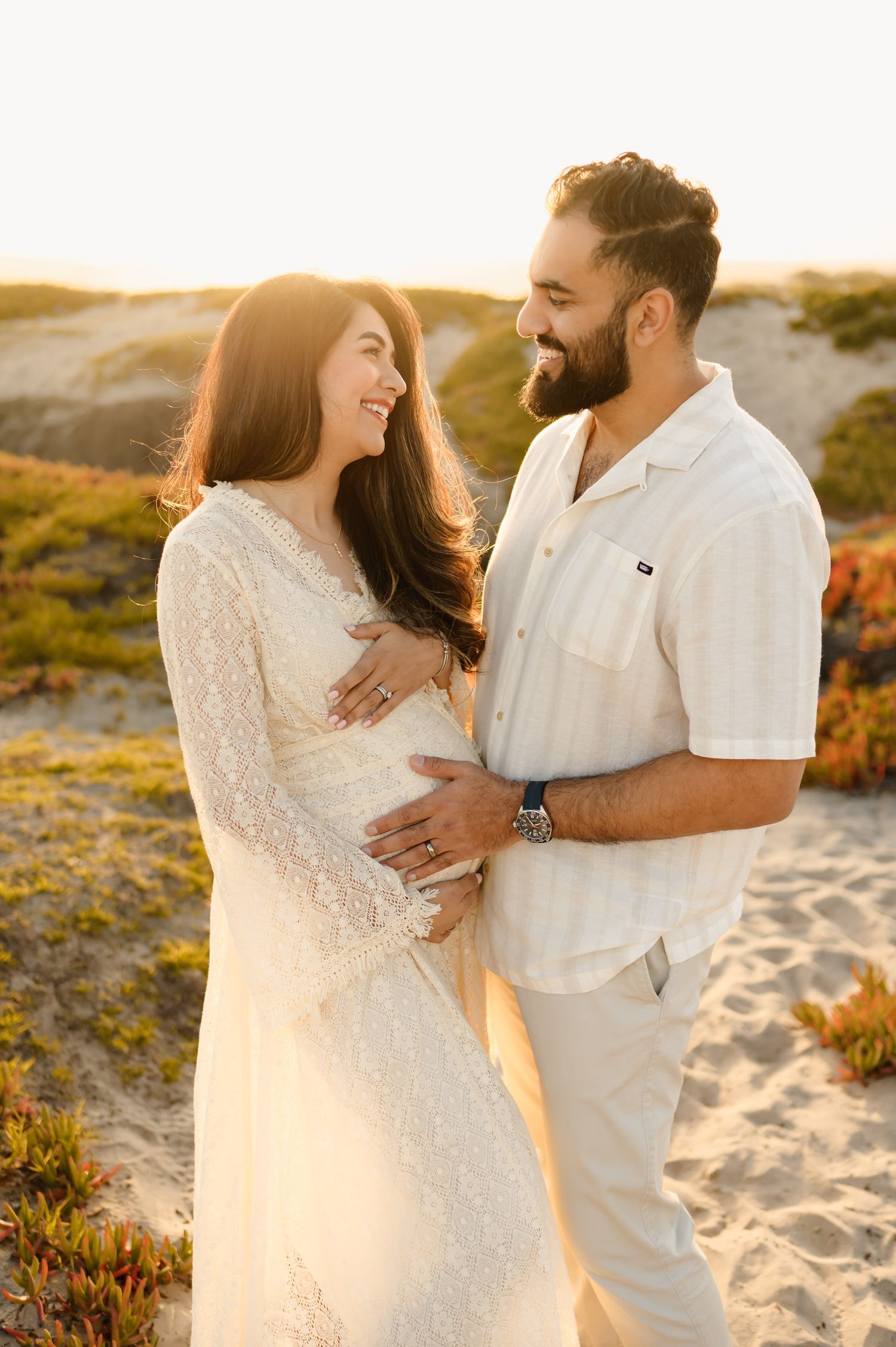 Santa Barbara babymoon beach maternity photoshoot by Ventura maternity photographer of couple standing on sand dunes during sunset