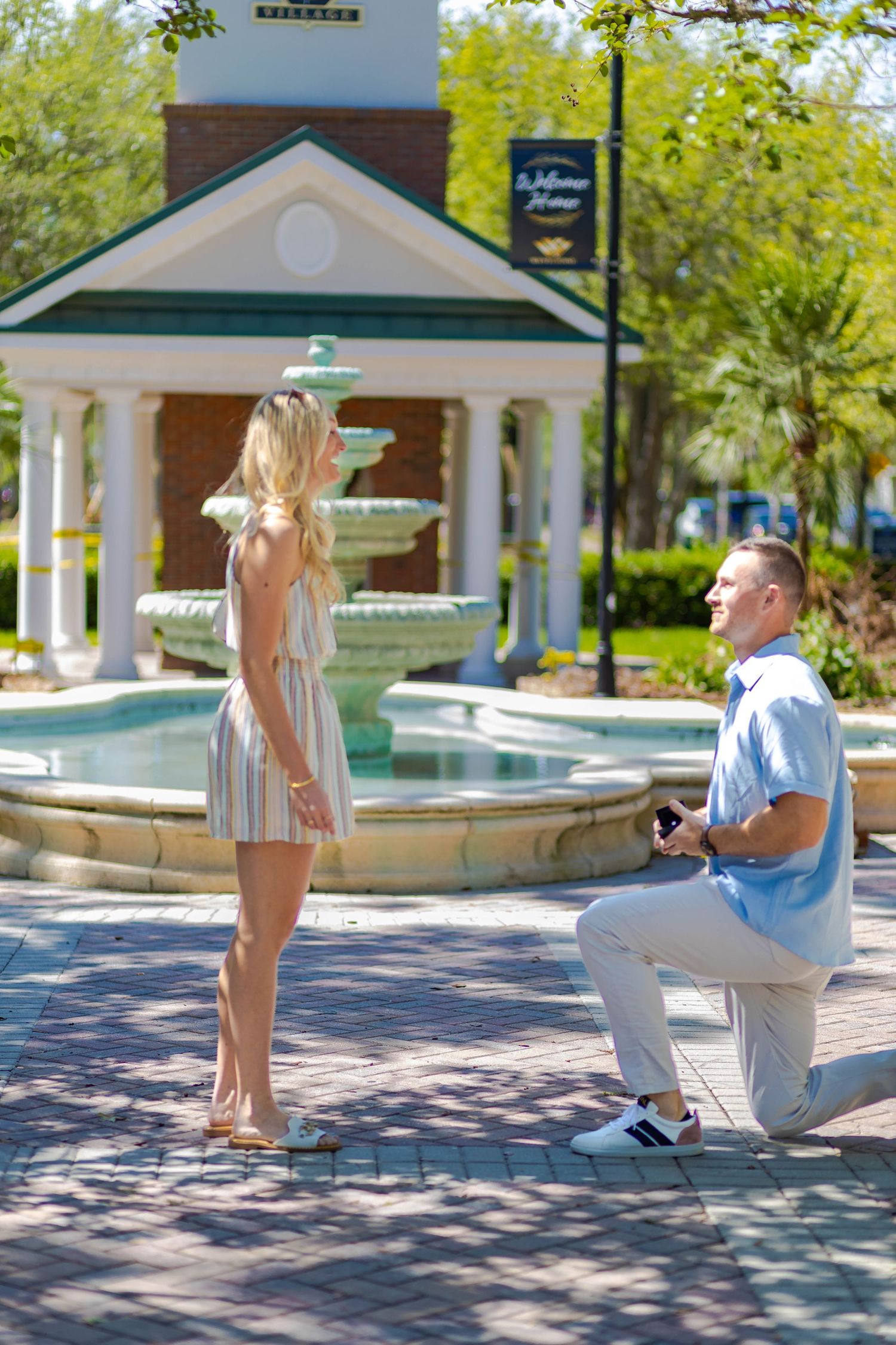 A romantic proposal scene by a fountain at an elegant outdoor venue.