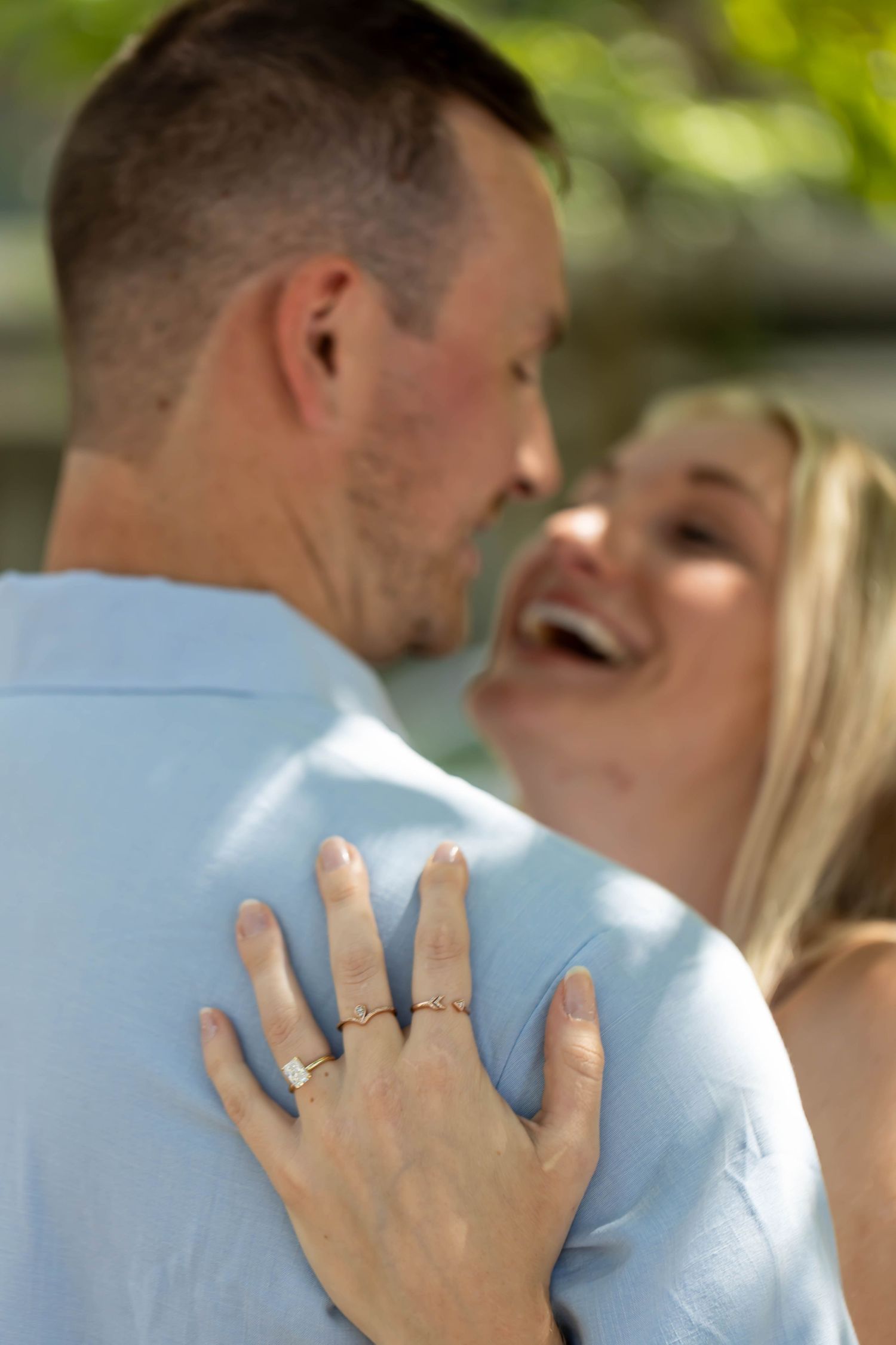 Close-up shot showing a hand with engagement ring resting on a light blue shirt.