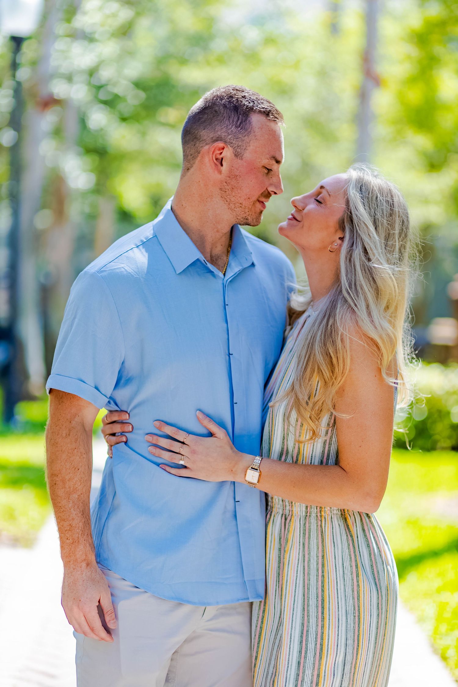 A romantic couple in coordinating outfits share an intimate moment in a sunlit garden.