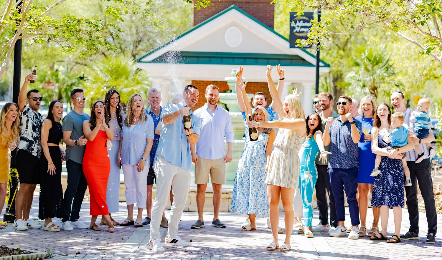 A large group of people celebrating a special moment outdoors near a gazebo.