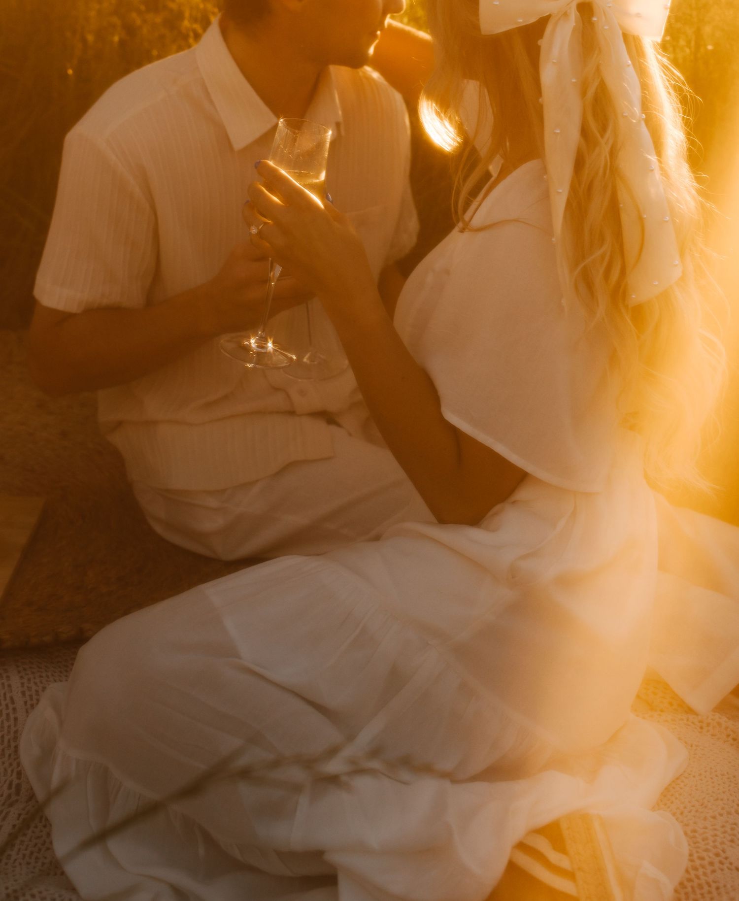 Dreamy golden hour portrait of couple in white attire.