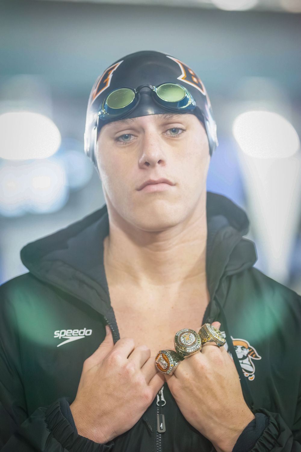Batesville, Arkansas high school senior swimmer wearing cap, goggles, parka and championship rings under the lights of the aquatics center