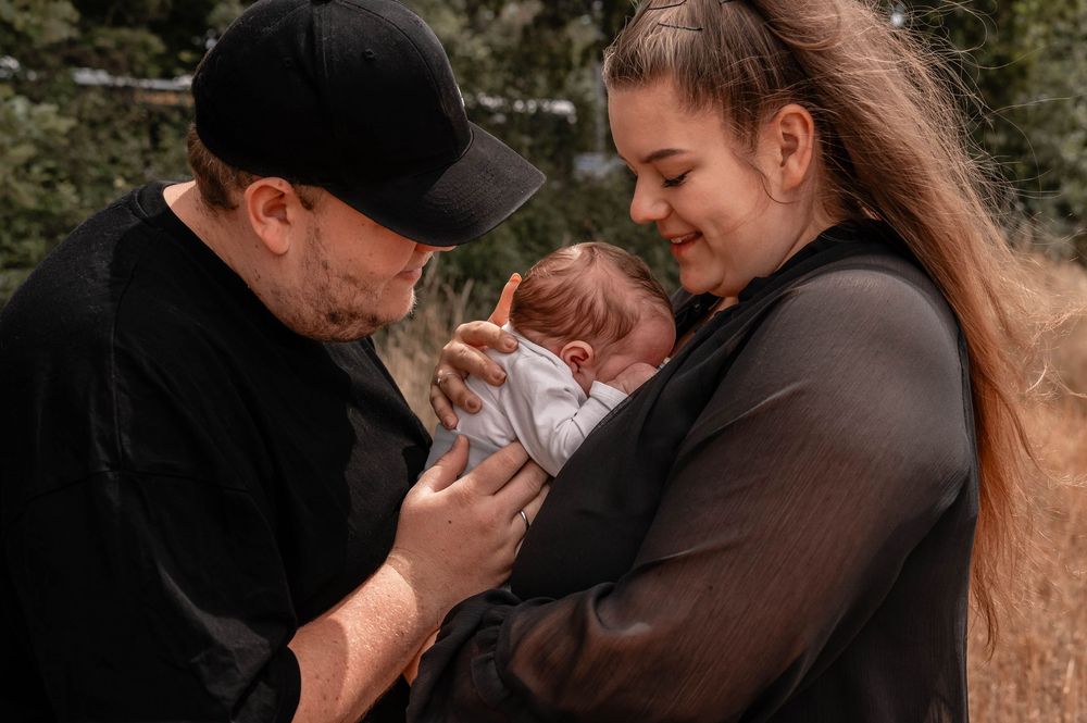 A romantic couple in black clothing embraces tenderly in a series of intimate outdoor portraits.