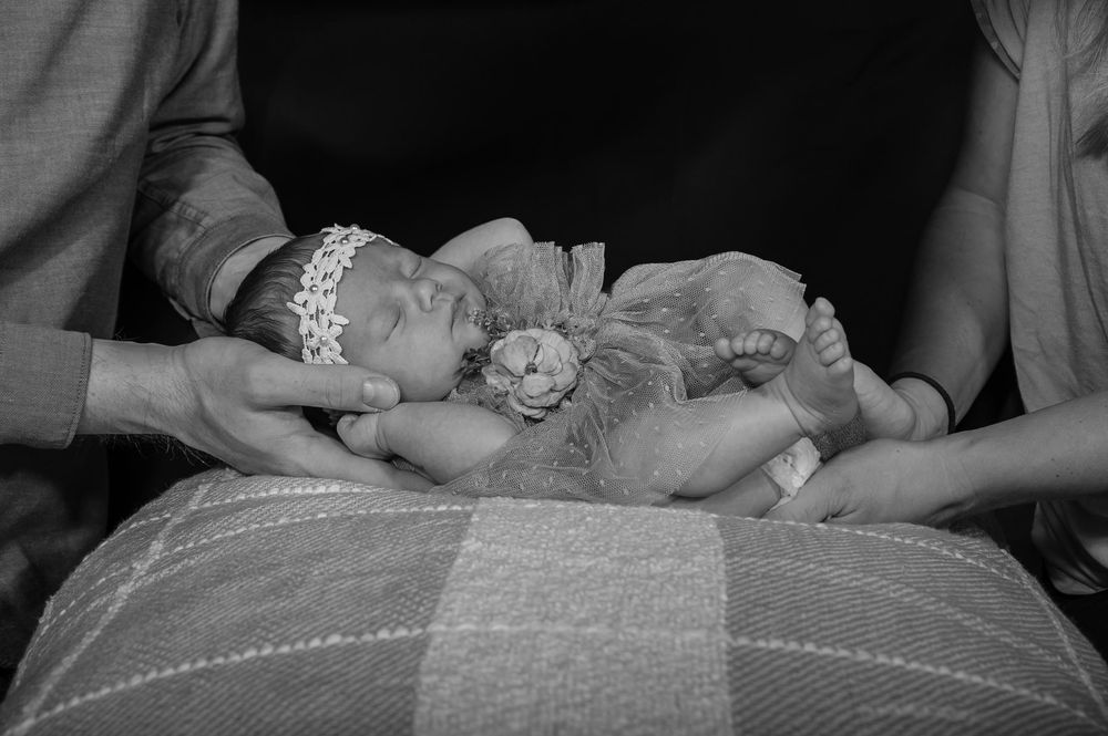 A black and white photo series showing a baby being swaddled in blankets on a changing table.