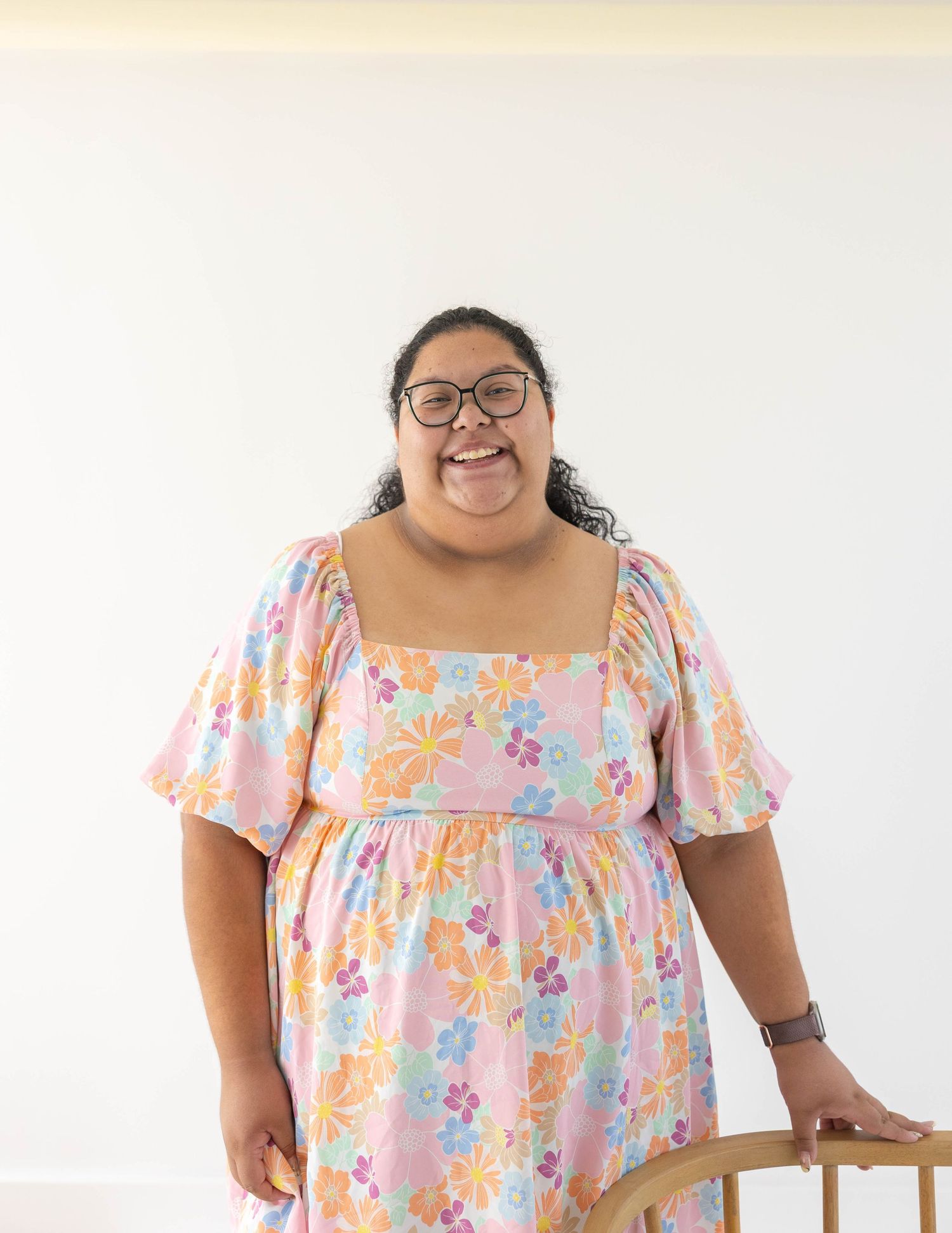 A person in a floral babydoll dress poses against a white background.