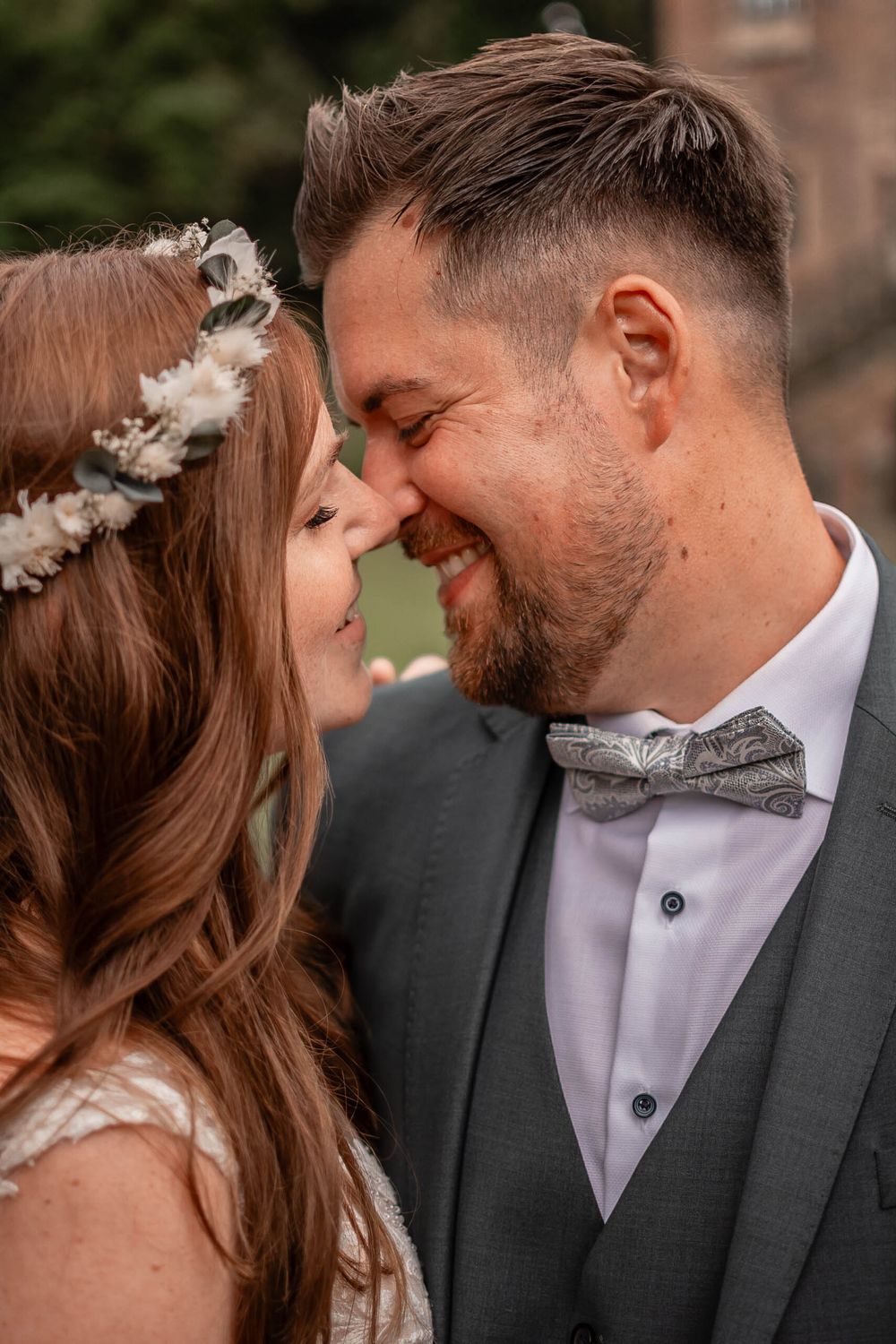 A touching close-up of a wedding couple sharing an intimate moment with their noses touching.