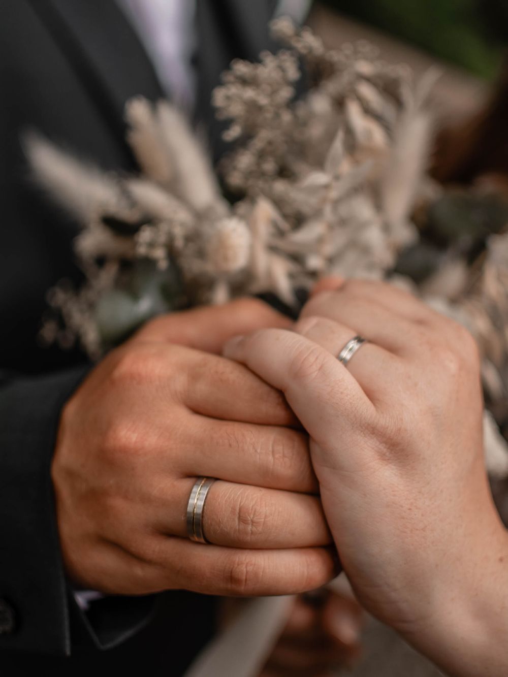 Two hands with wedding rings come together in a tender embrace showing eternal love and commitment.