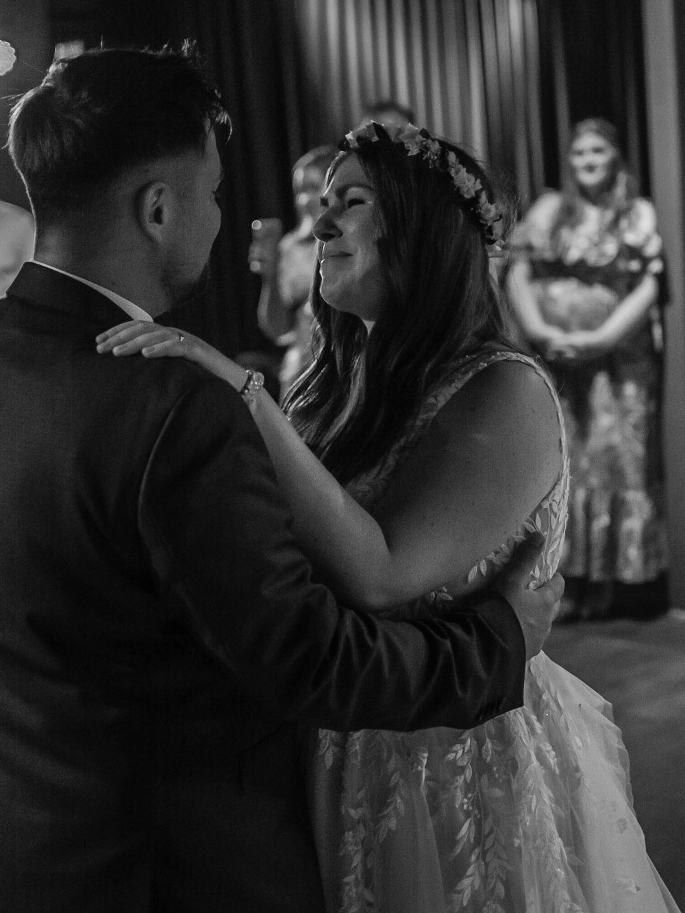 Newlywed couple shares an intimate dance on a dimly lit dance floor during their wedding reception.