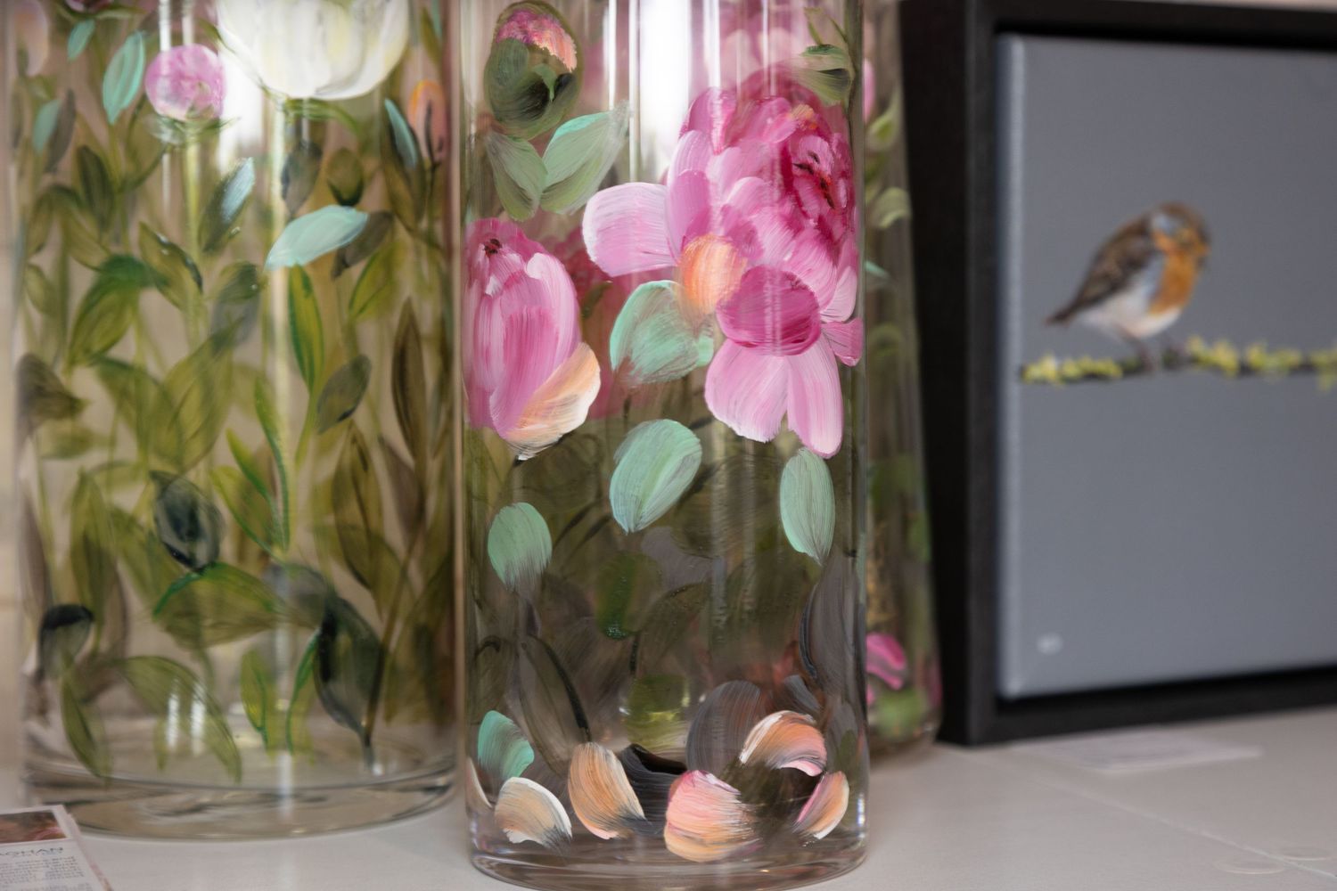 Close up of Flower glass art on a vase, and a painted Robin in a frame.
