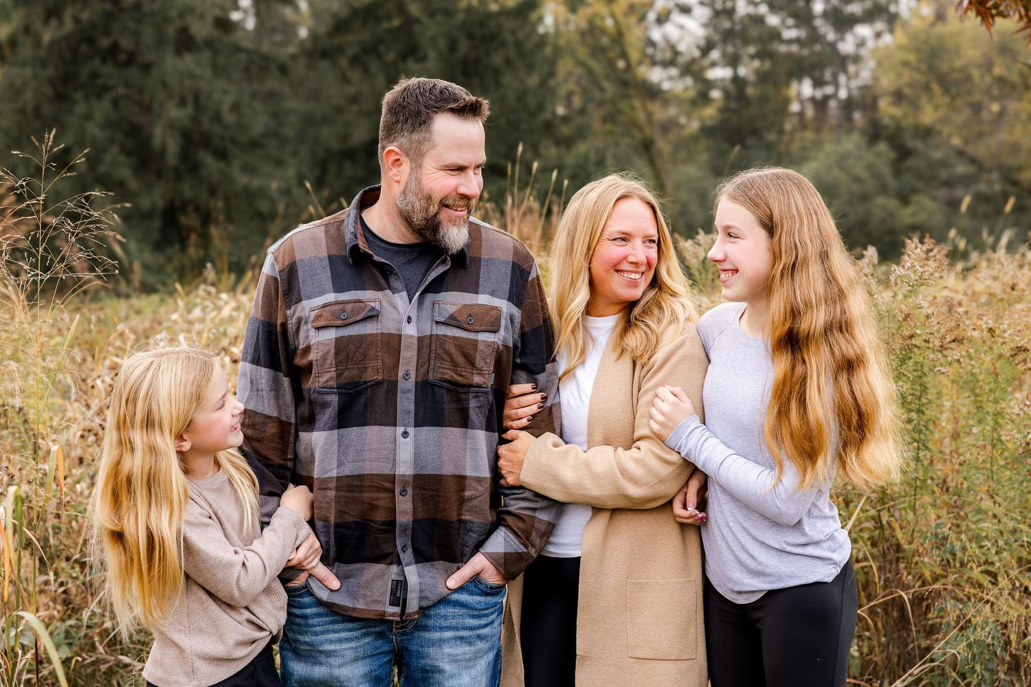 A loving family of three share an intimate moment together against a white background while wearing winter sweaters.