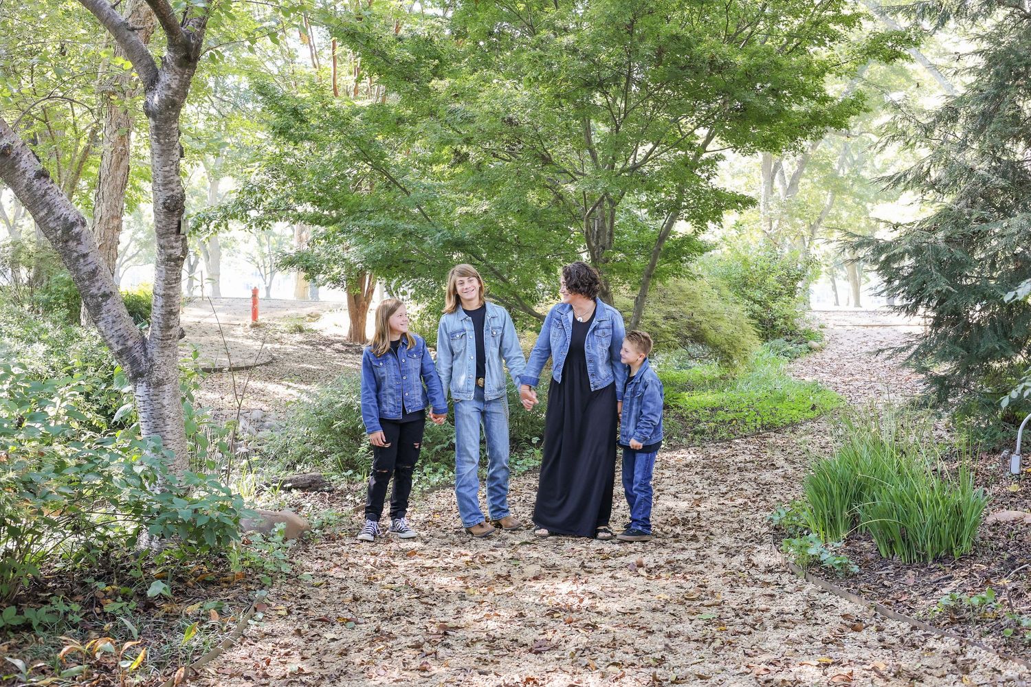 Group walking through wooded path surrounded by green trees.