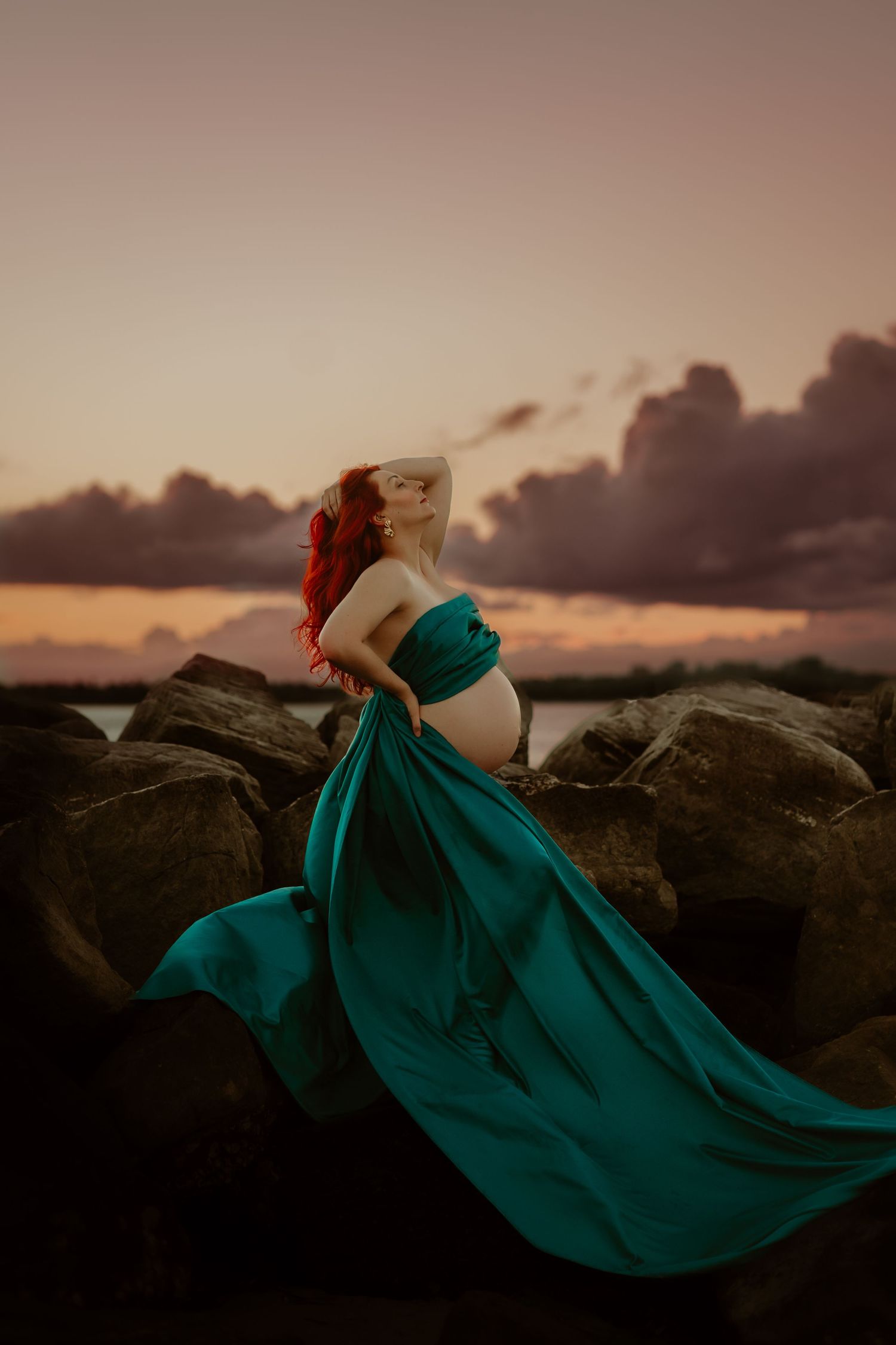 Woman in white dress lying on beach shore during golden sunset.
