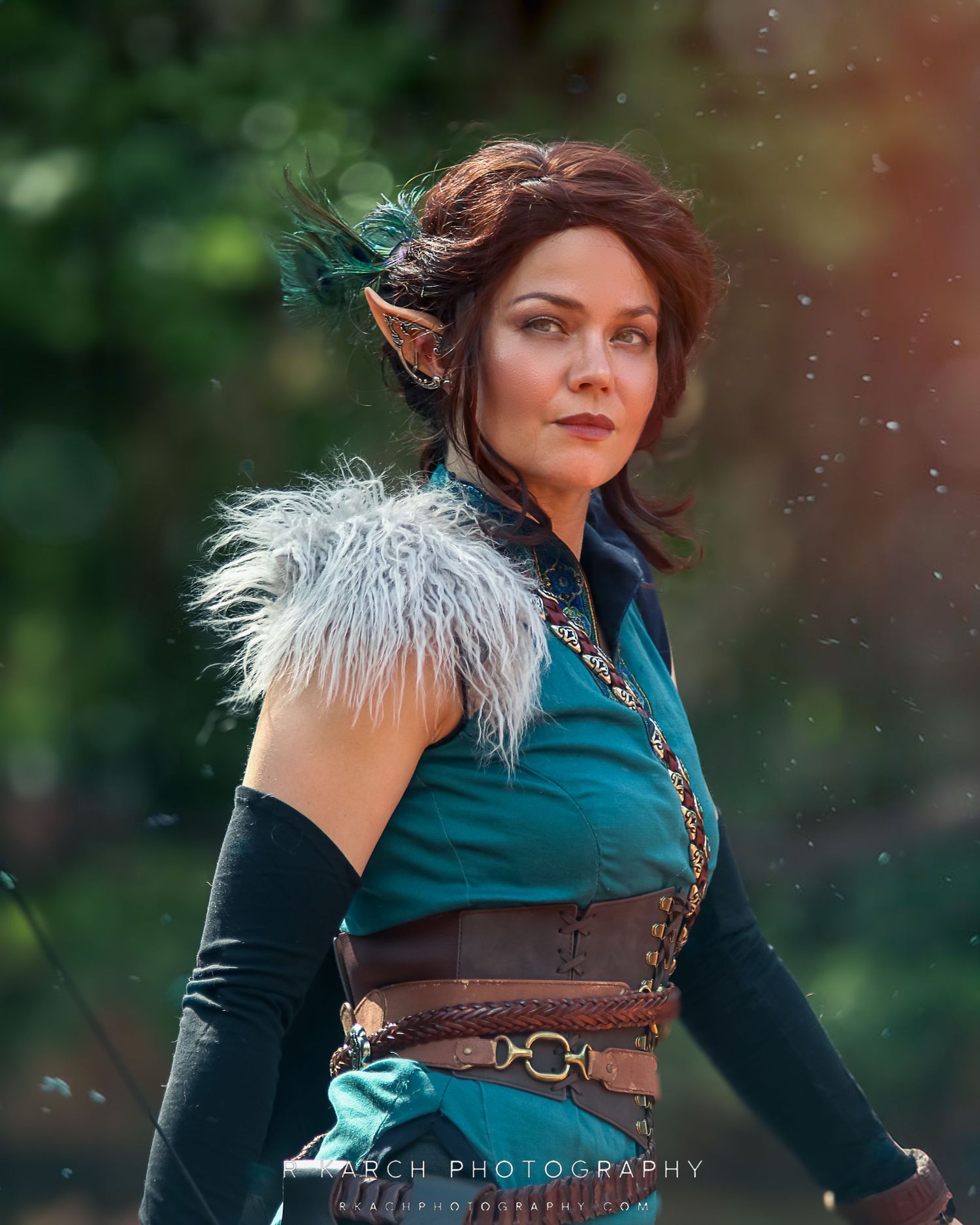 A costumed performer in a teal dress with fur shoulder detail and steampunk-inspired accessories at an outdoor event.
