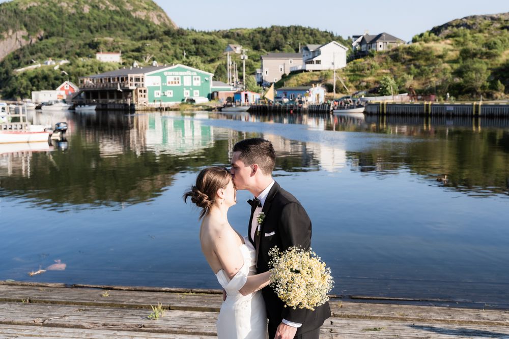 A couple sharing a kiss at Quidi Vidi, with the picturesque harbor and charming surroundings of St. John's, Newfoundland
