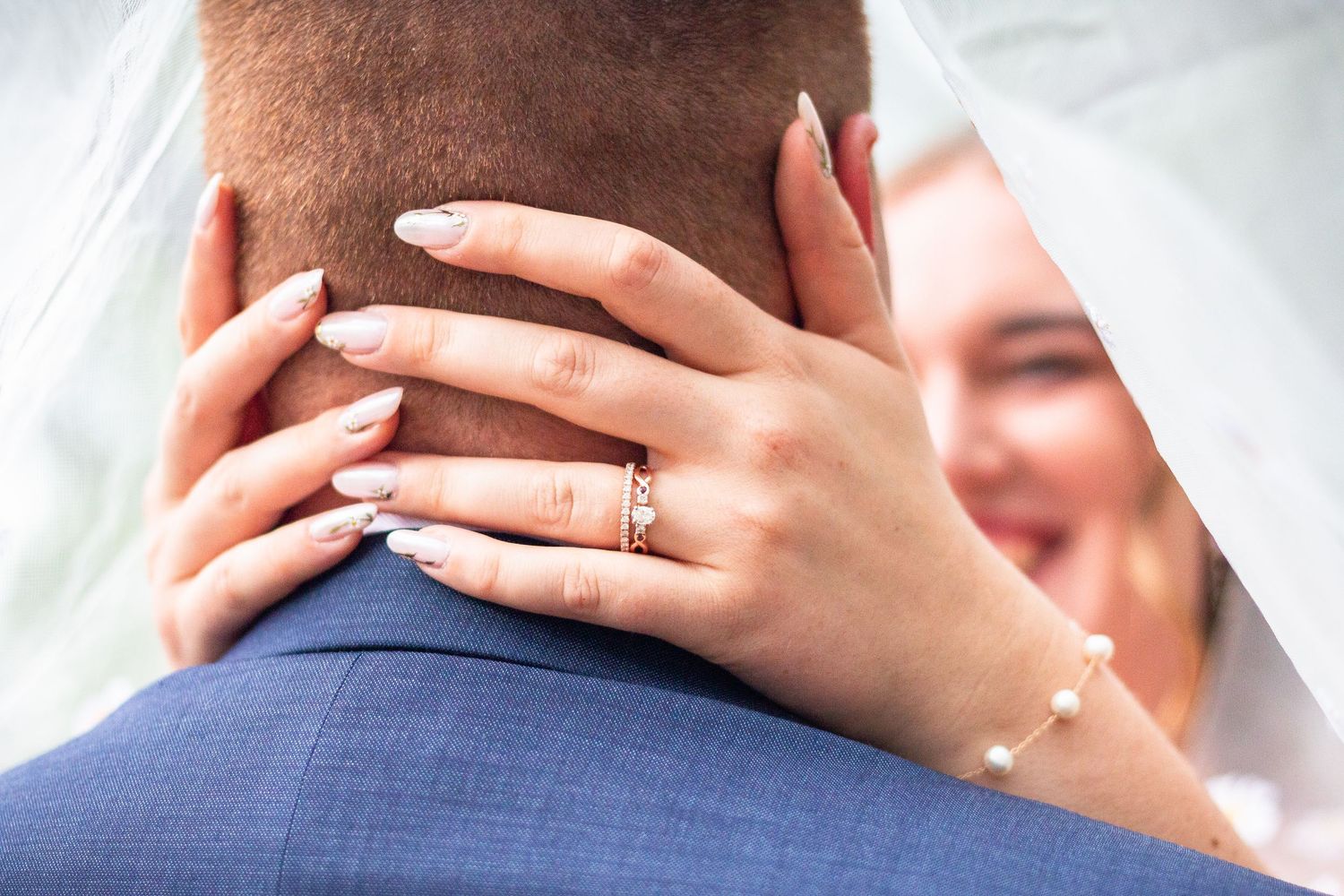 A romantic couple shares a tender kiss while embracing against a bright background.
