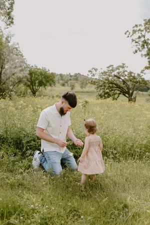 Parent and child share tender moment while playing in tall grass meadow.