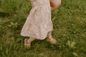Motion blur of pink dress twirling in green grass field.