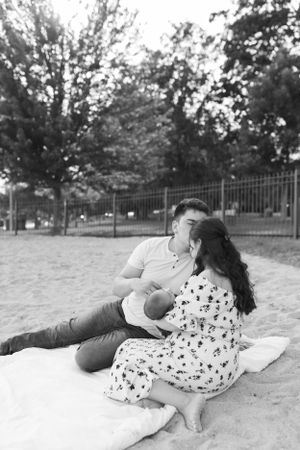 Black and white family portrait on beach blanket with newborn baby.