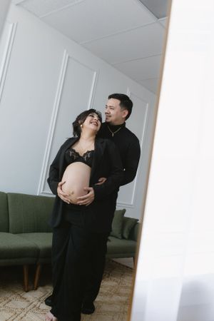 Intimate maternity portrait in minimalist setting with couple in black attire.