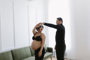 Couple sharing intimate maternity dance moment in bright minimalist room.