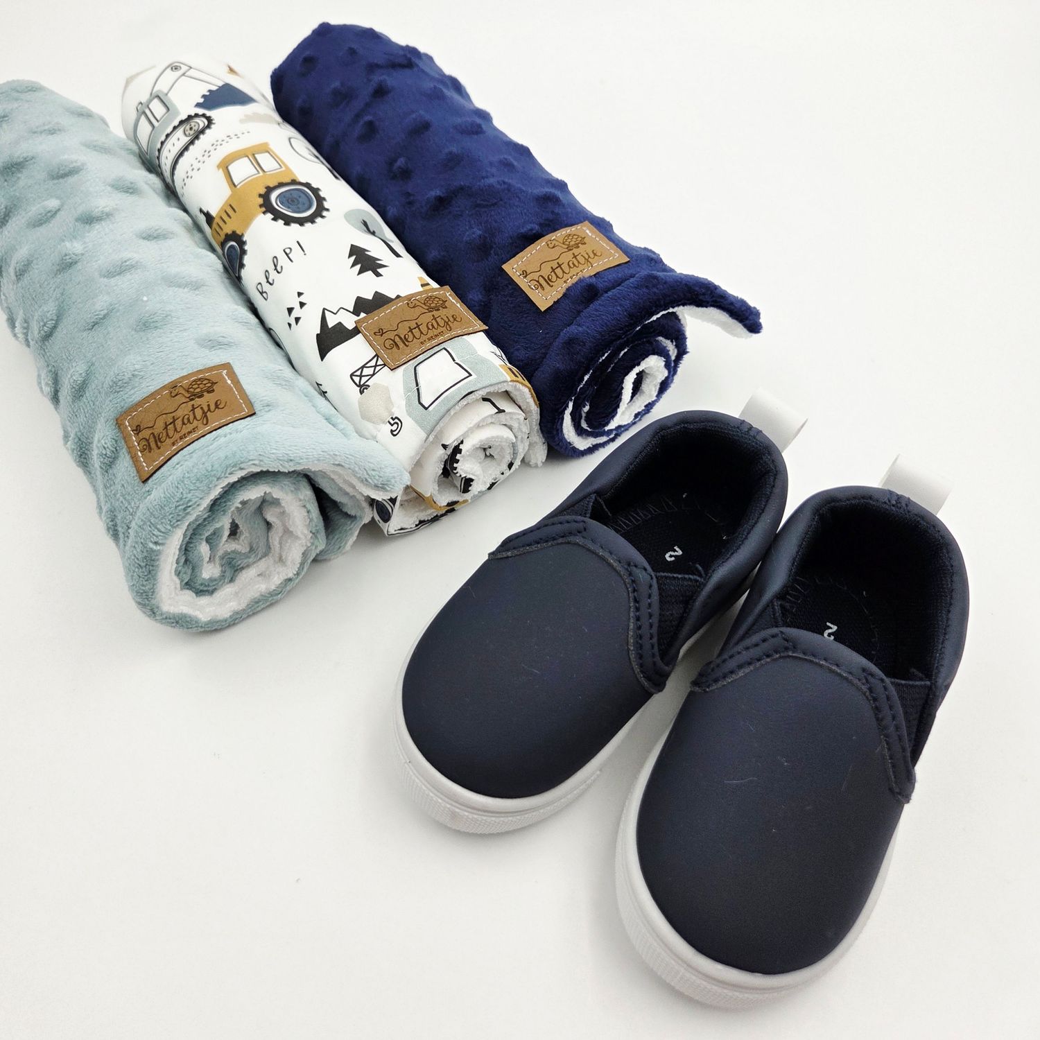Navy blue and mint green baby blankets with matching navy leather shoes.