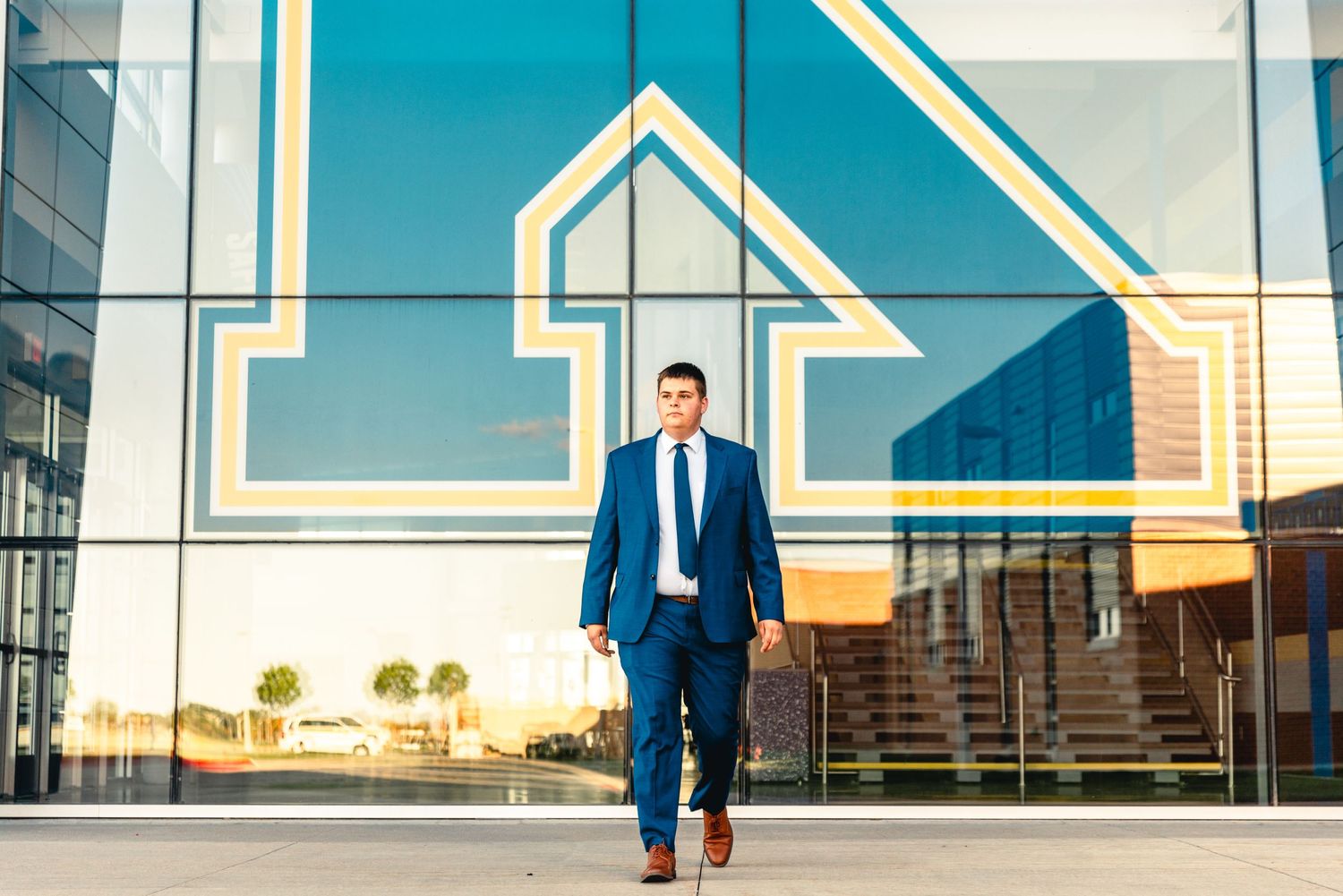 Business professional stands in front of modern building with geometric arrow design.