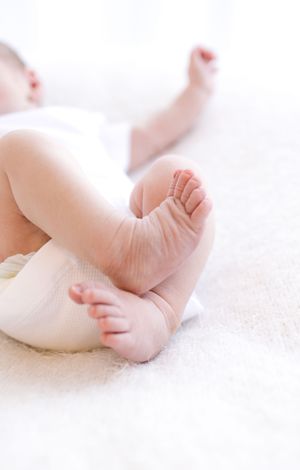 Close-up of a baby's tiny feet and toes resting on a soft white blanket.