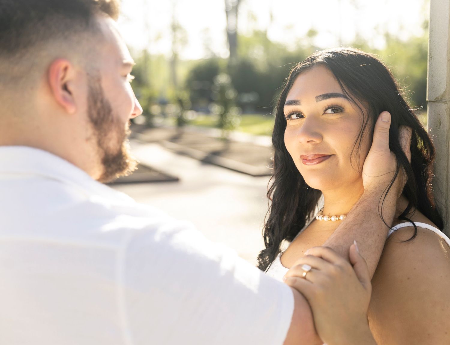 A tender romantic moment between a couple in warm sunlight with soft focus and natural outdoor setting.