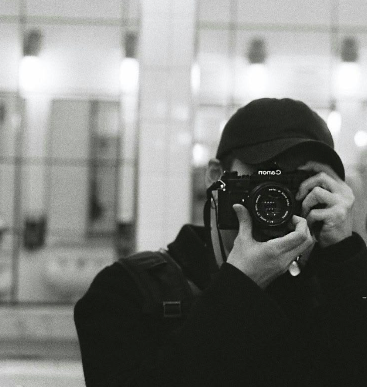 Black and white self-portrait of photographer holding a Nomo camera in a mirror.