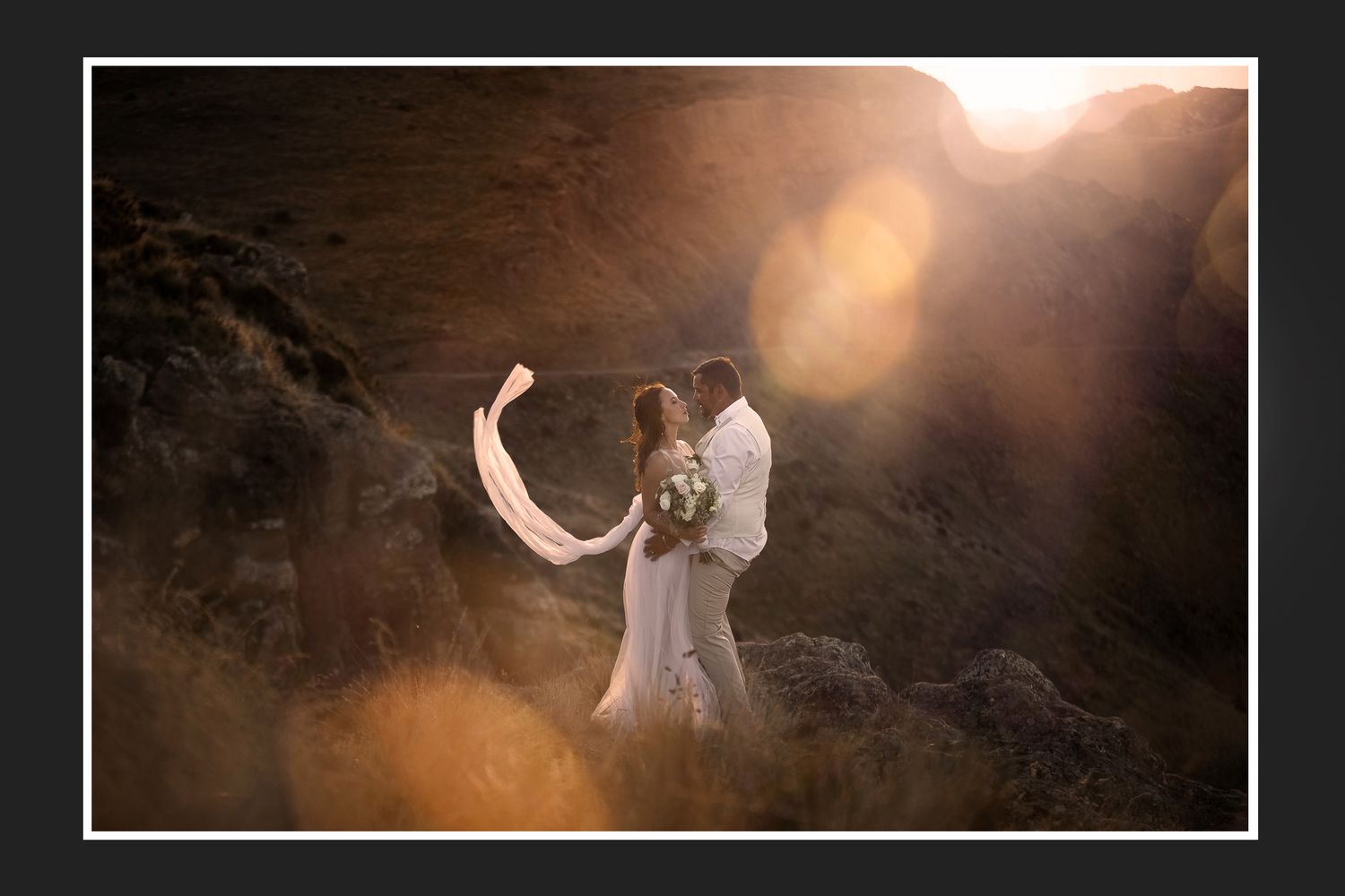 A couple walks together in a scenic mountain valley with snow-capped peaks in the distance.