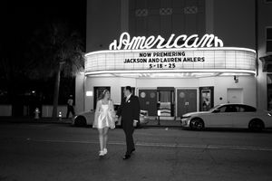 Vintage black and white photograph of a classic American movie theater marquee illuminated at night.