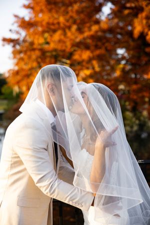 A romantic wedding kiss sequence captured against vibrant autumn foliage in orange and red hues.
