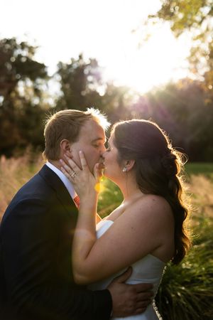 Newlyweds share romantic sunset kisses in a garden with golden sunlight streaming through Spanish moss trees.