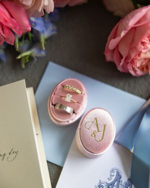 Pink macarons and delicate wedding stationery arranged on light blue surface.